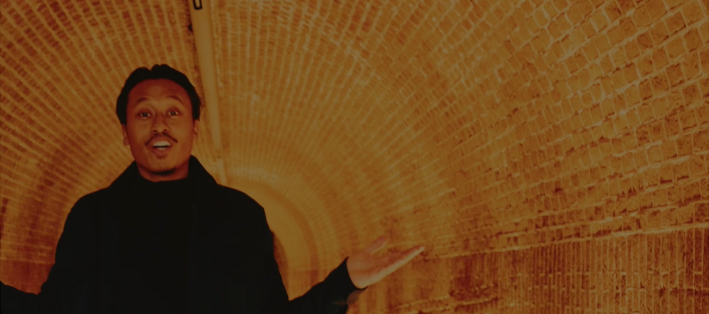 A host welcoming visitors into one of Fort bij Vechten's brick-vaulted bunker tunnels