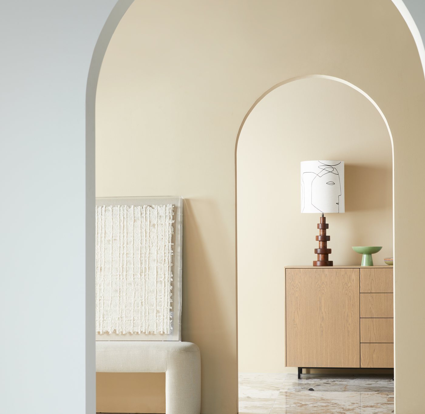 A sequence of arched doorways through the Het Kabinet Wonen showroom, styled with art and a cabinet