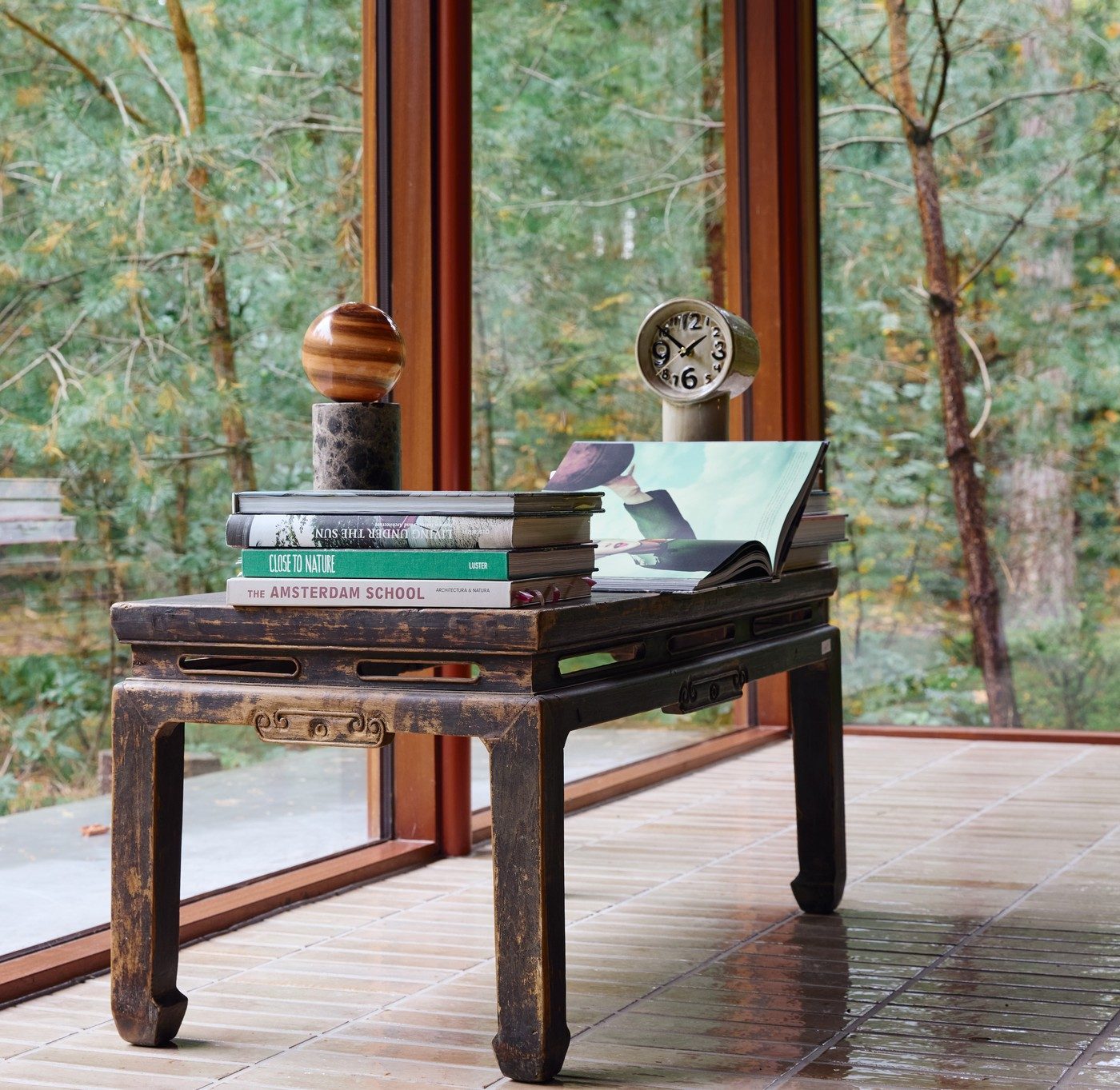 A weathered Chinese elm side table styled with a wooden sphere, ceramic clock and vintage books