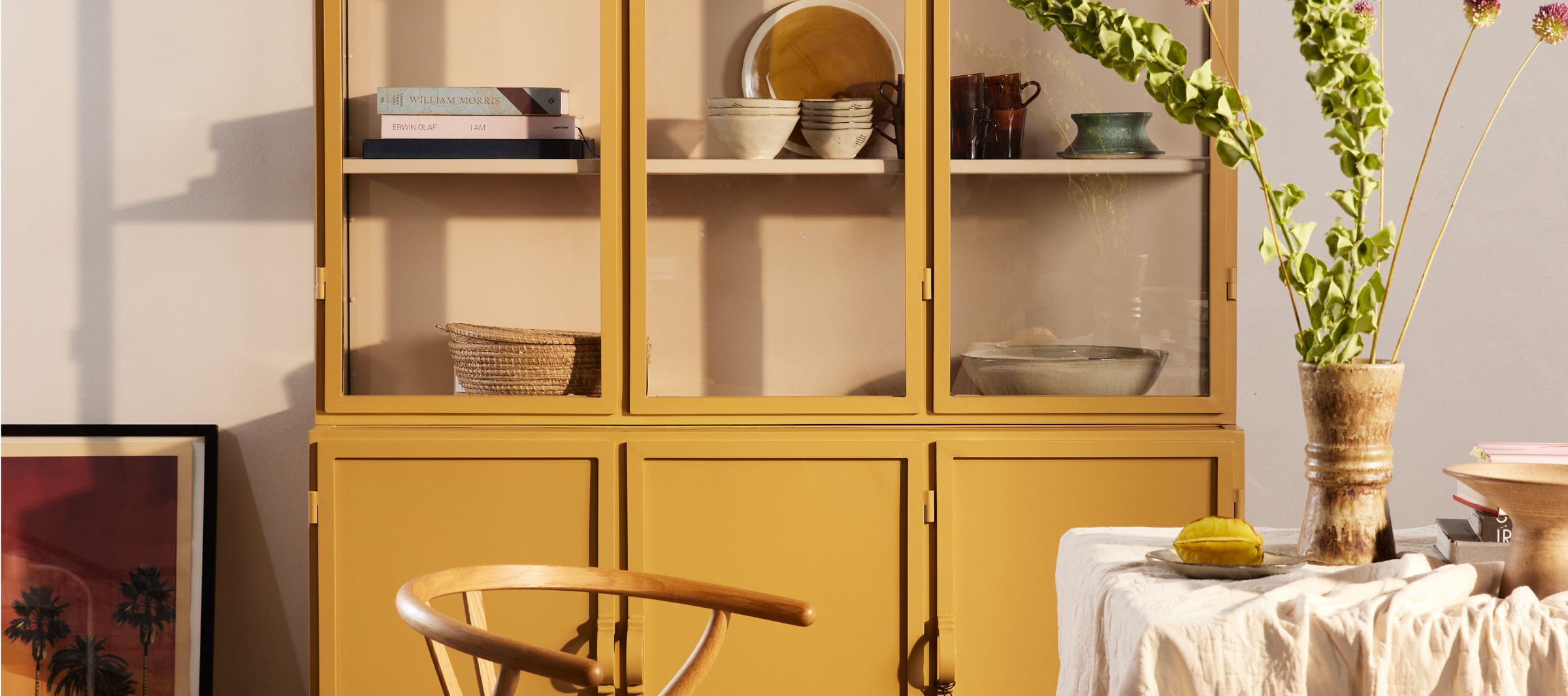 A New Routz mustard-yellow cabinet styled with ceramics, books and a trailing plant